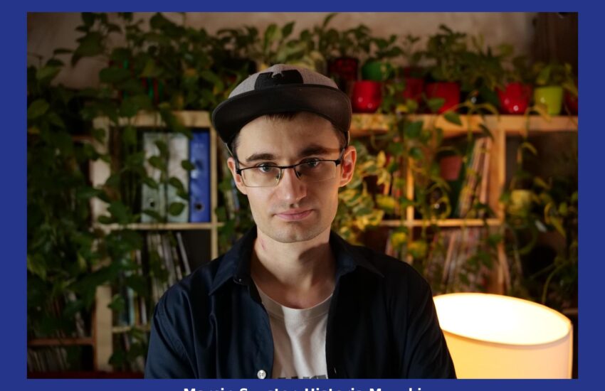 Zdjęcie portretowe Marcina Szustera, w czapce z daszkiem i okularach, na tle półki z książkami i płytami