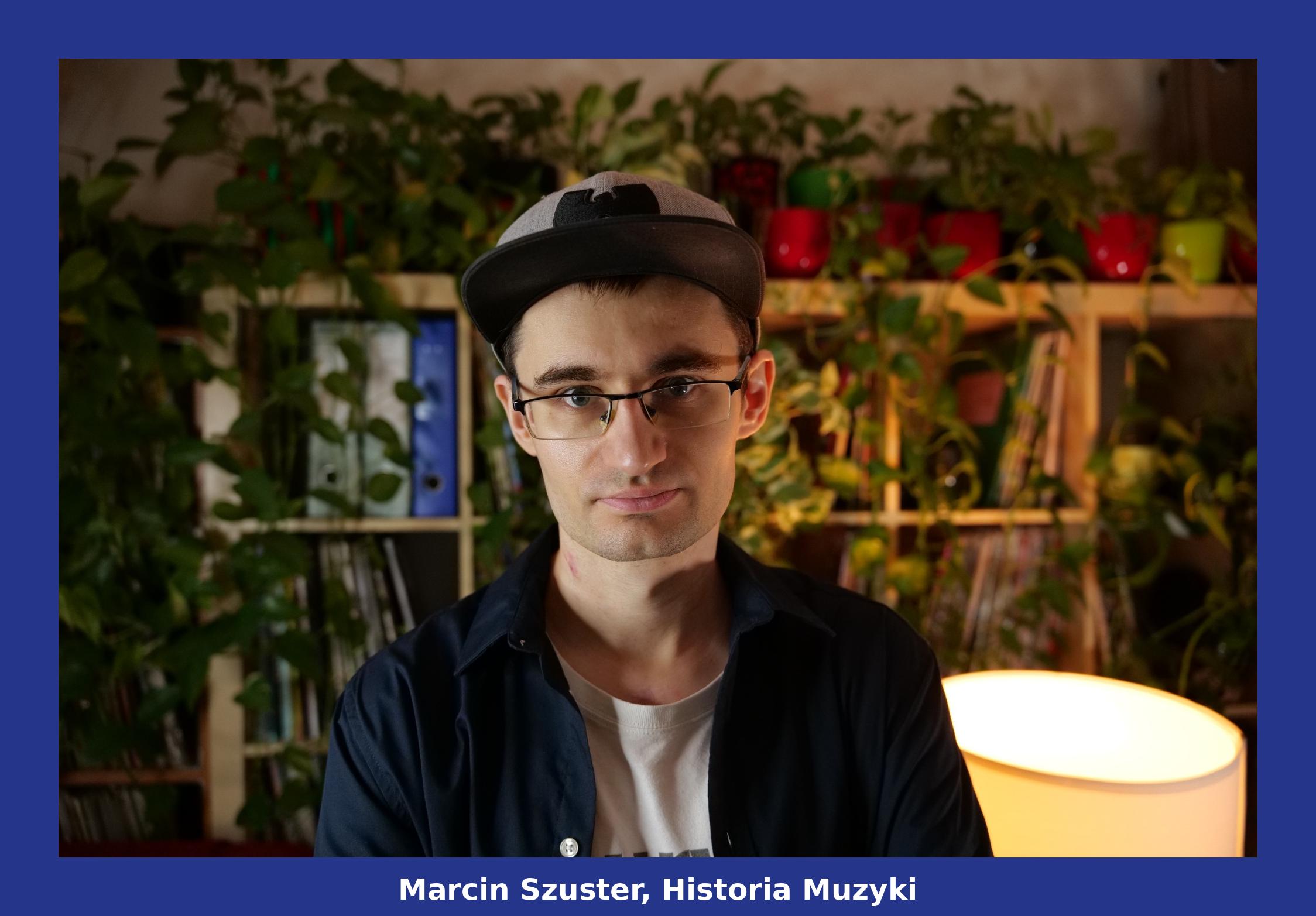 Zdjęcie portretowe Marcina Szustera, w czapce z daszkiem i okularach, na tle półki z książkami i płytami